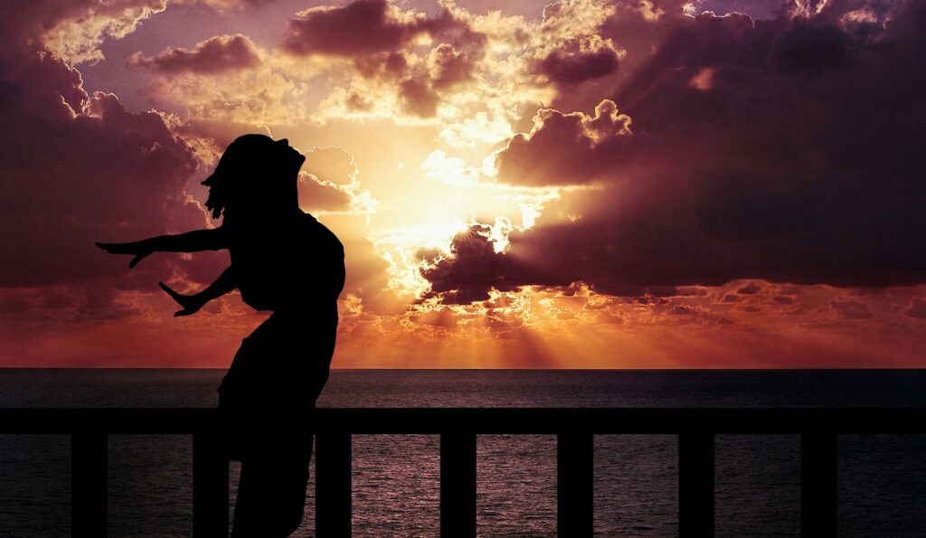 Silhouet van een vrouw die de vrijheid voelt bij zonsondergang, passend bij het loslaten in de alleenstaande moeder dochter relatie.